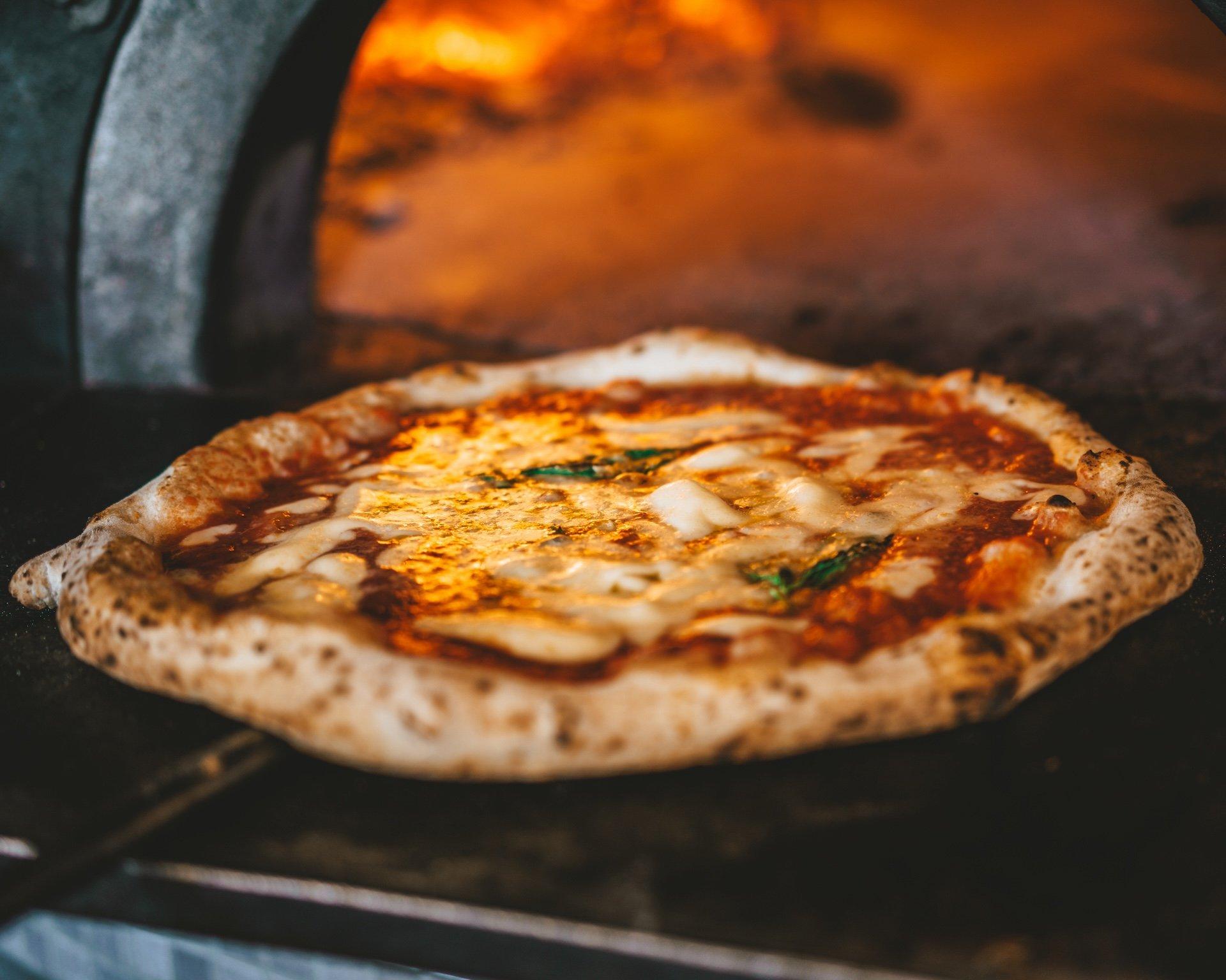 pizza coming out of wood oven