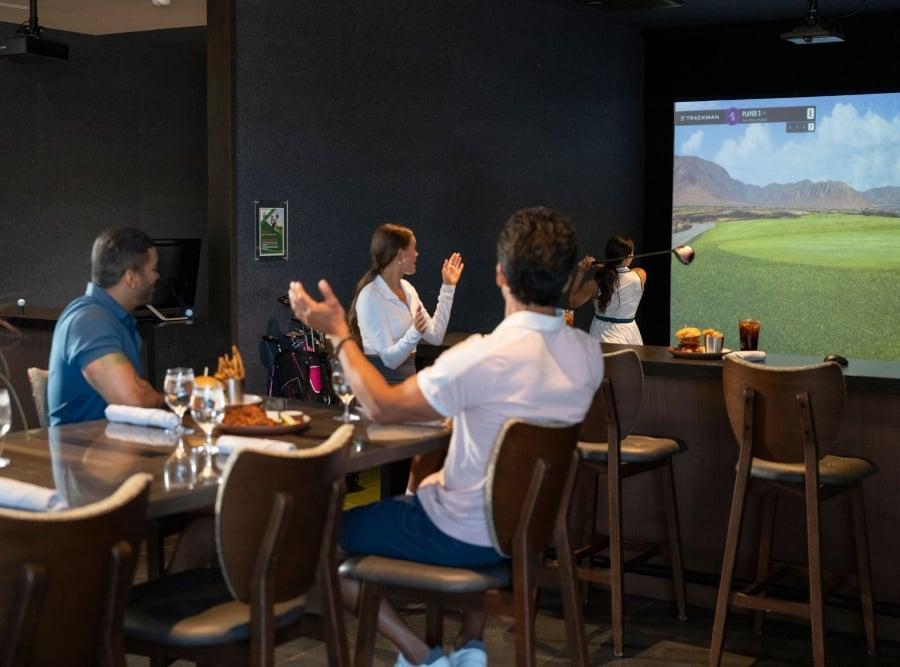 A group watching someone take a swing on a golf simulator
