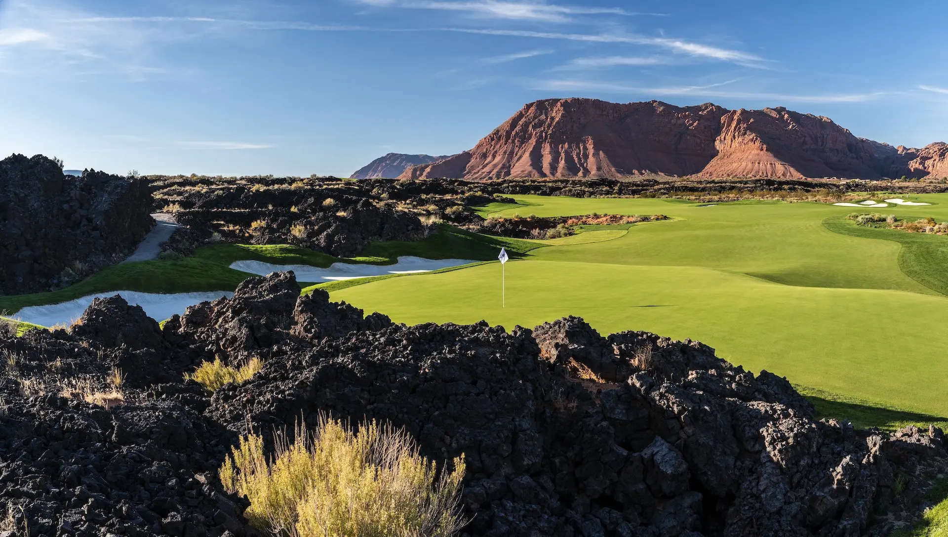 The expansive, illuminated 18-hole putting course at Black Desert Resort, showing the massive green and clubhouse glowing at sunset.