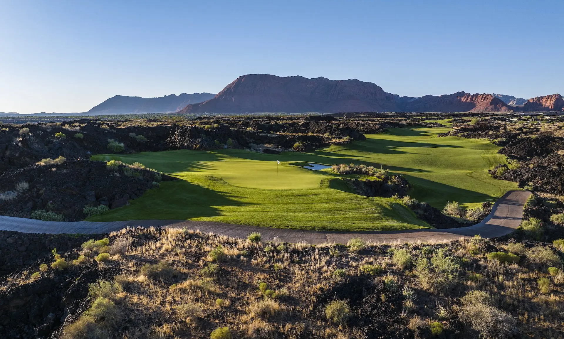 The stunning golf course at Black Desert Resort, where a lush putting green and white sand traps are carved directly into ancient black lava fields.