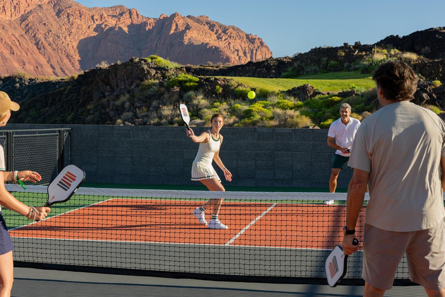 Guests enjoying a pickleball match at Black Desert Resort surrounded by red rock vistas and black lava fields.